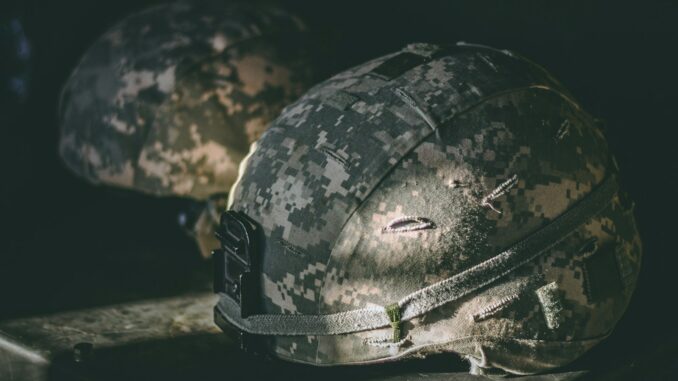 gray and brown camouflage nutshell helmet on table